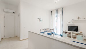 Ein modernes, minimalistisches Wohnzimmer mit Essbereich, einem Flachbildfernseher und einer integrierten Unterhaltungseinheit.