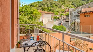 Ein Balkon mit Tisch und Stühlen, der einen Blick auf einen Hügel mit Gebäuden und einer Straße bietet.
