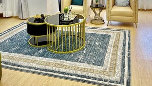 A modern living room with a beige sofa, a round black and gold coffee table, and a patterned rug. - Stardust Apartments (Abuja)