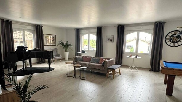 Un salon spacieux comprenant un piano, un canapé, une table basse et une table de billard.