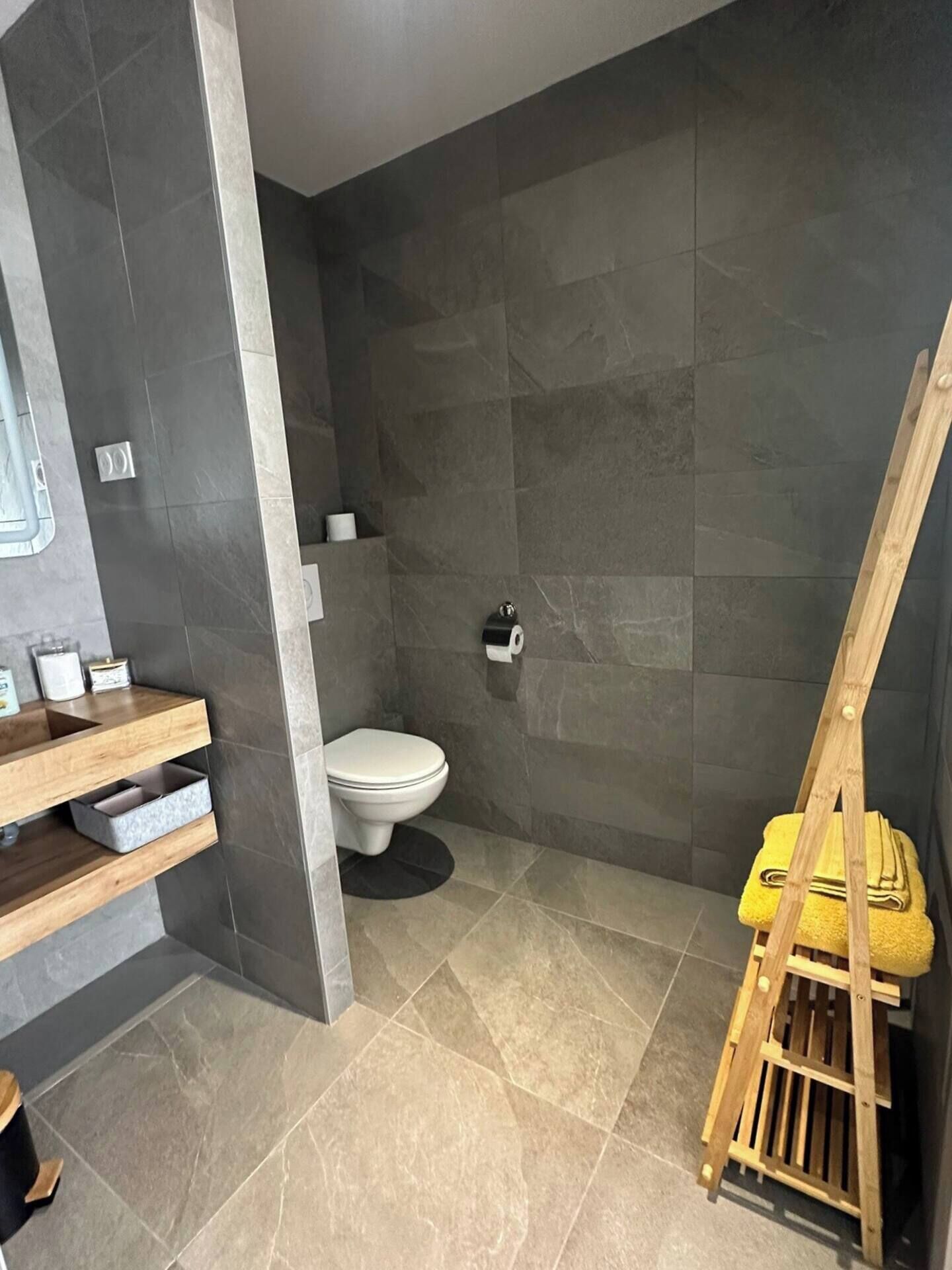 Een badkamer met toilet, een houten wastafel en een houten trap.