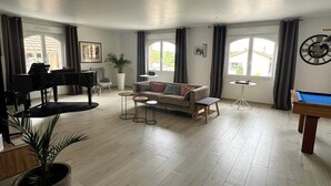 Un salon spacieux comprenant un piano, un canapé, une table basse et une table de billard.