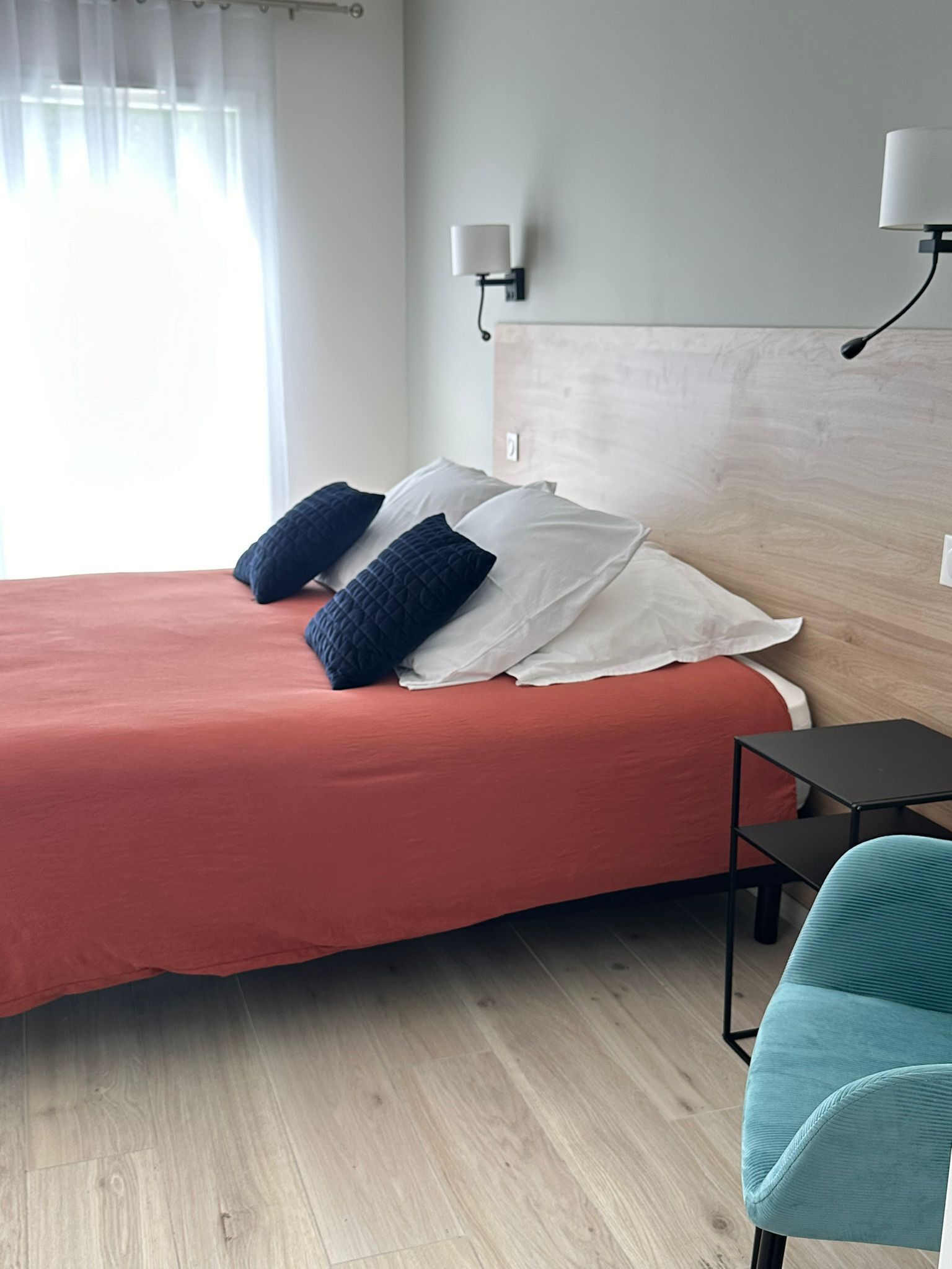 Une chambre d’hôtel avec un grand lit, deux tables de chevet, une petite table et une chaise.