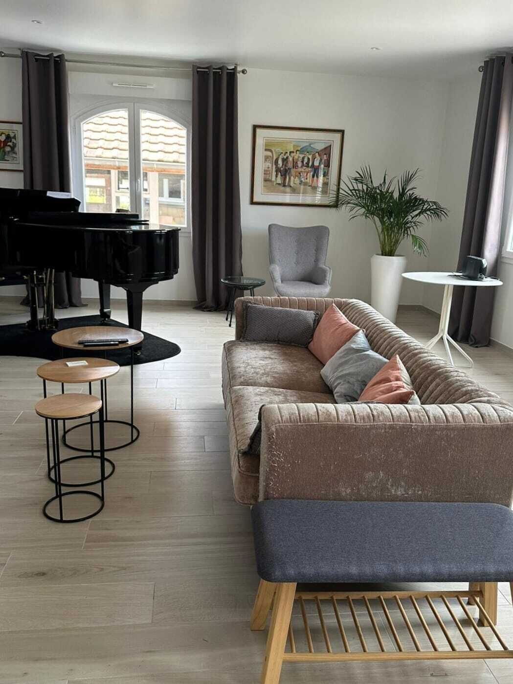 Een woonkamer met een vleugelpiano, een bank, een salontafel en een bijzettafeltje.