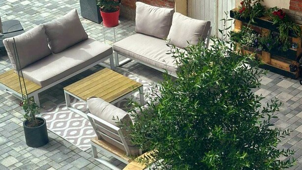 Un espace patio comprenant un jardinier rond, un ensemble de canapés et une table à manger.