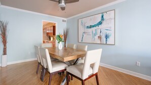 A dining area with a wooden table and six chairs, a ceiling fan, and a large abstract painting on the wall. - Historic District, Walkable w/Free Parking & Patio (Savannah)