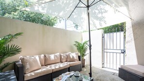 A patio area with a sofa, a table with a tray set, and potted plants. - Historic District, Walkable w/Free Parking & Patio (Savannah)