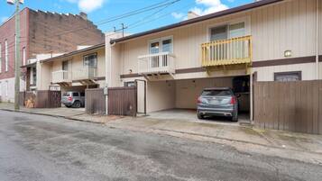 A two-story residential building with a garage, a balcony on the second floor, and a parked car in the driveway.