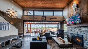 A spacious living room with a stone fireplace, a large TV, and a wooden ceiling. - Treehouse at the Wilderness Club (Eureka)