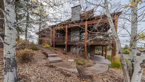 A rustic cabin with a stone chimney, wooden deck, and a winding stone pathway. - Treehouse at the Wilderness Club (Eureka)