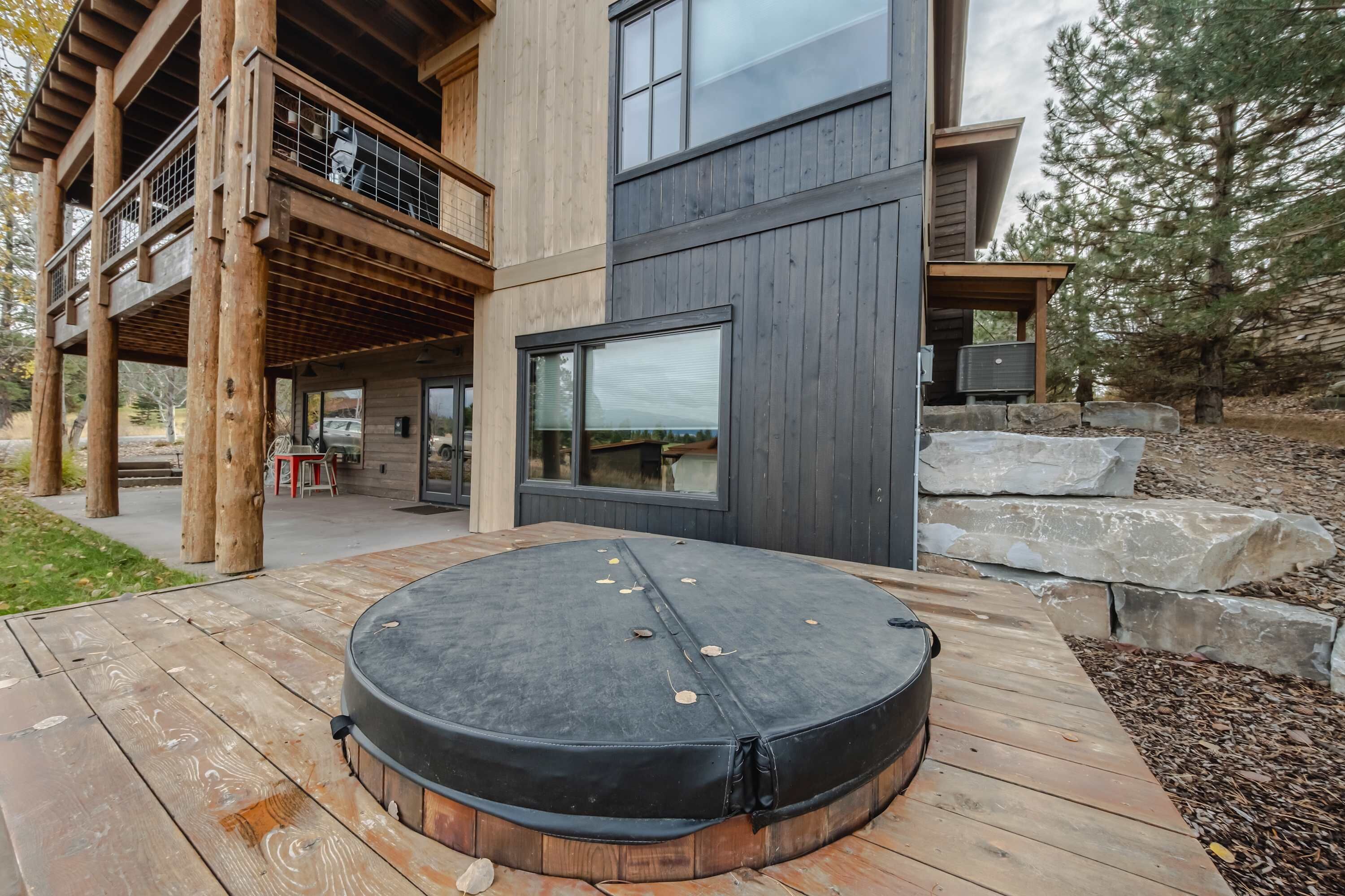 A modern outdoor hot tub on a wooden deck with a wooden deck and a stone wall in the background.