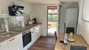 A modern kitchen with white cabinets, a wooden countertop, a built-in oven, and a dining area with a table and chairs.