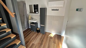 A modern bathroom with a wooden staircase, a sink, and a shower area.
