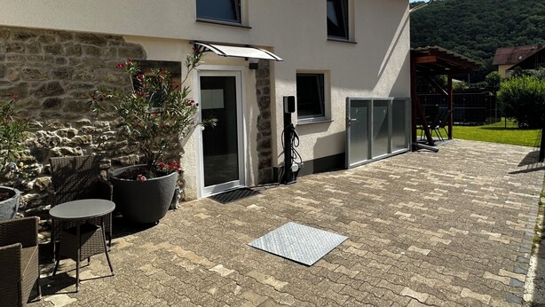 A building with a stone facade, a covered patio with outdoor furniture, and a door leading to an interior space.