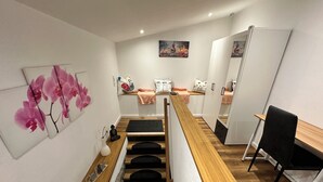 A modern room with a wooden desk, a black chair, a bed with a pink blanket, and a painting of pink flowers.