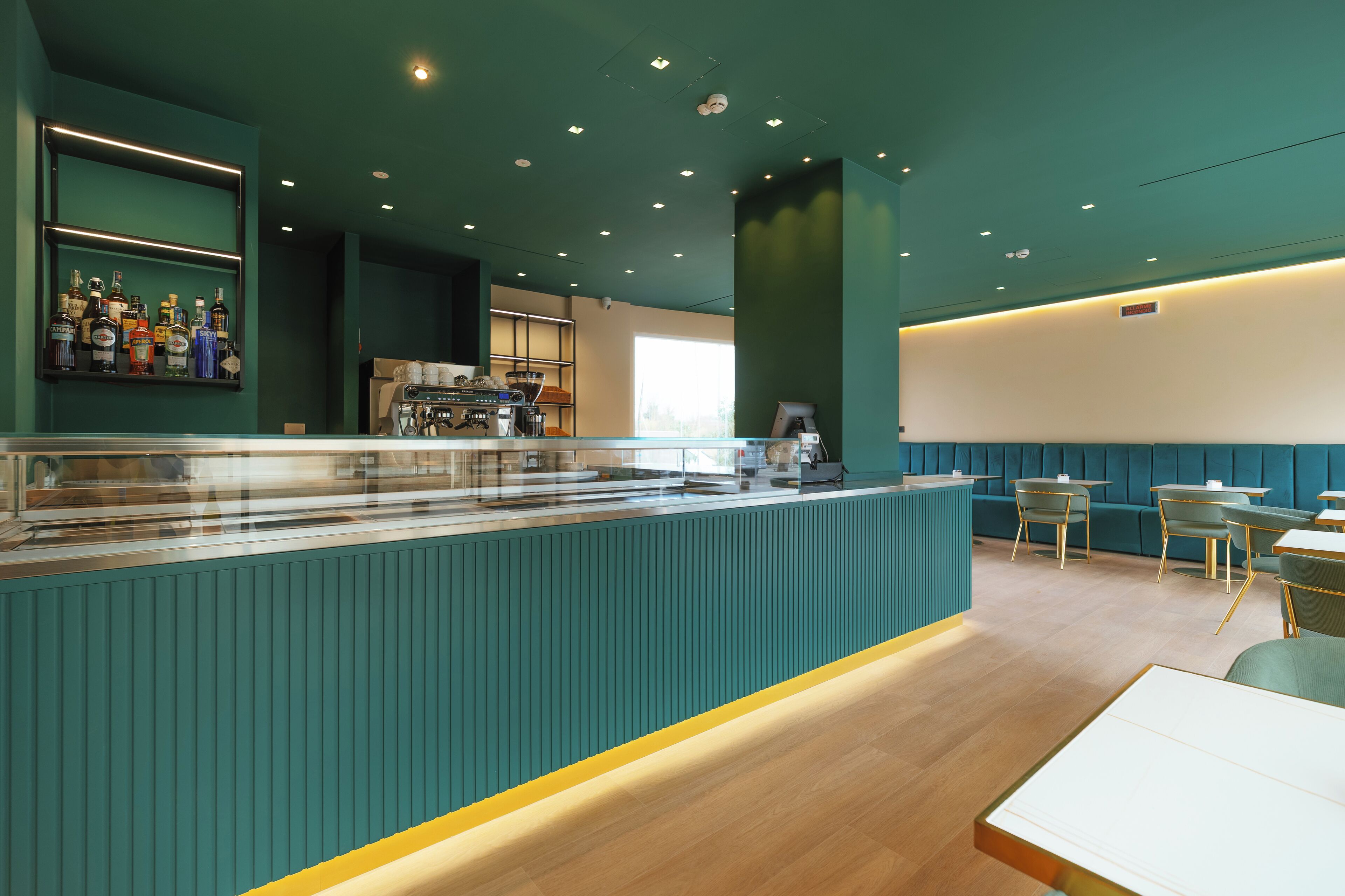 Un área de bar moderna con mostrador, asientos y una exhibición de botellas.
