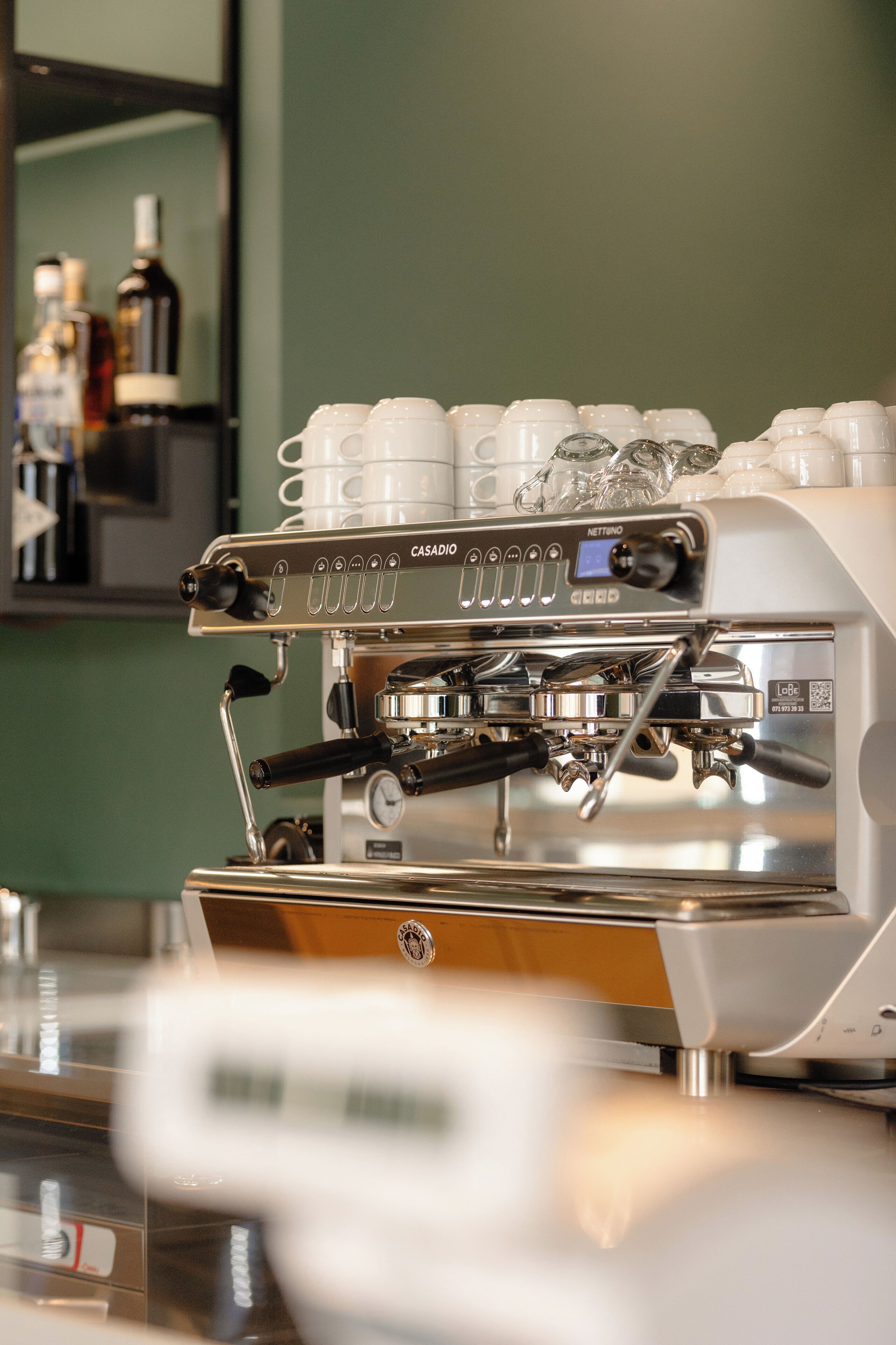 Una cafetera con varias tazas de café y una pantalla digital.