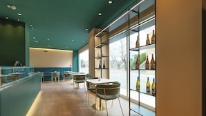 Un intérieur de restaurant moderne avec un plancher en bois, des murs de couleur turquoise et une vitrine où sont exposées des bouteilles.