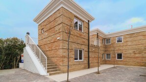 Un immeuble à plusieurs étages, doté d’une façade en briques, d’un escalier blanc et de nombreuses fenêtres.