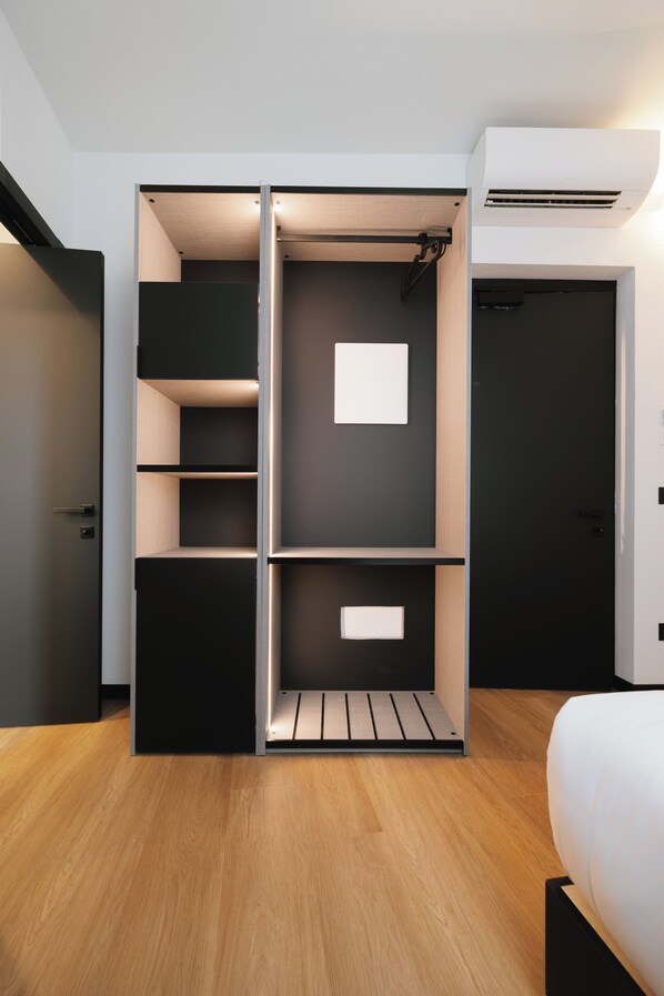 A modern bedroom with a built-in wardrobe, a bed, and an air conditioning unit. - Aspio Hotel (Camerano)