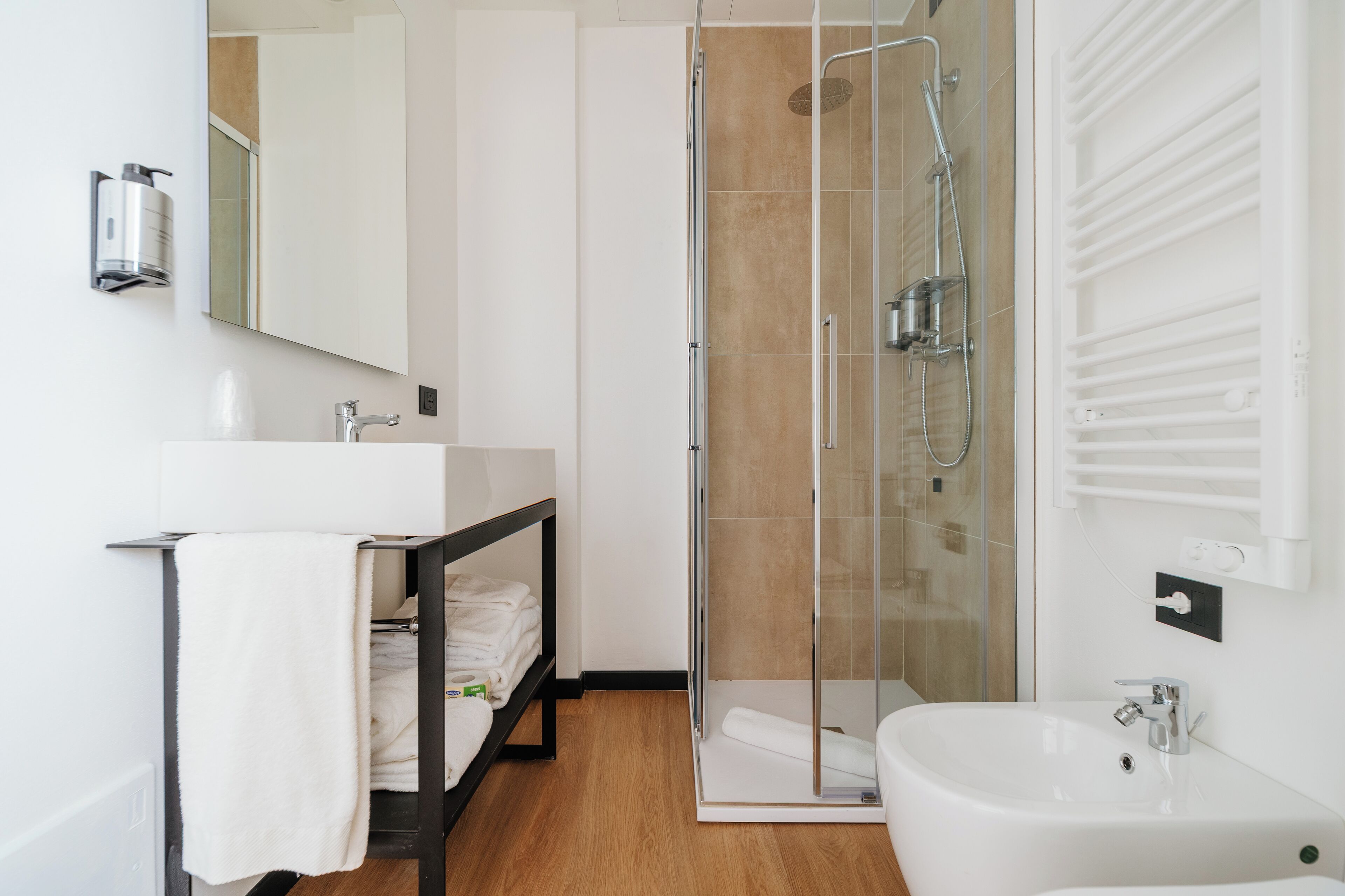 Een moderne badkamer met een douchecabine van glas, een witte wastafel en een handdoekhouder.