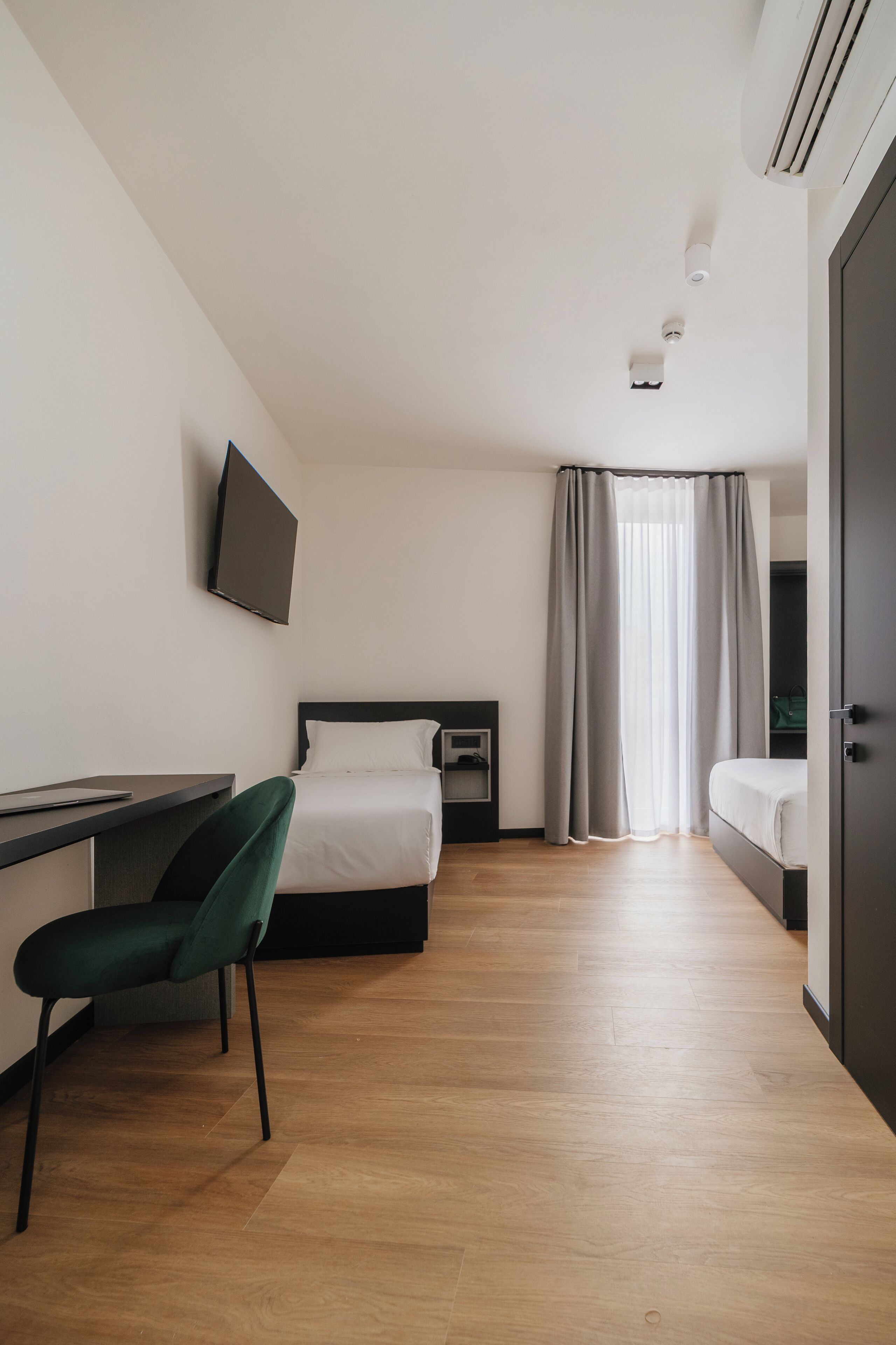 A hotel room with a bed, a desk, a chair, a television, and a wardrobe.
