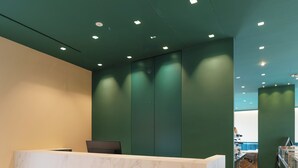 Un espace d’accueil doté d’un comptoir en marbre, de murs verts et d’un éclairage encastré.