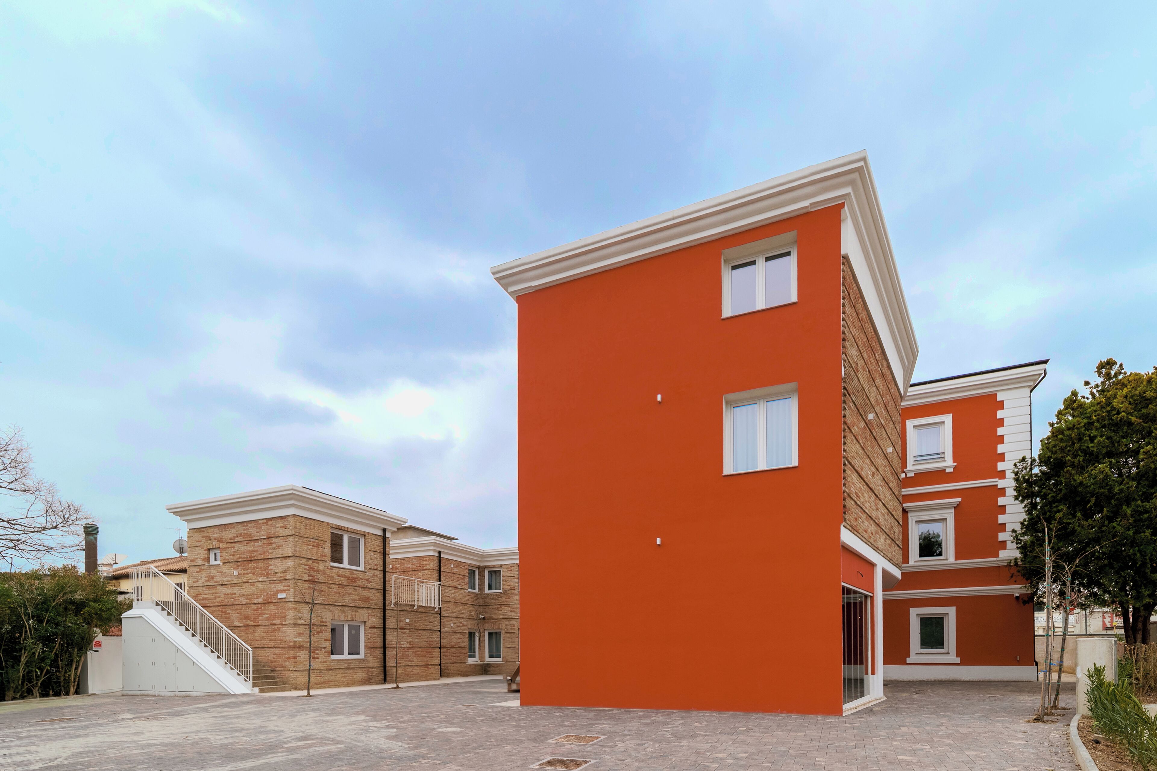 A modern multi-story building with a brick facade and a bright orange exterior.