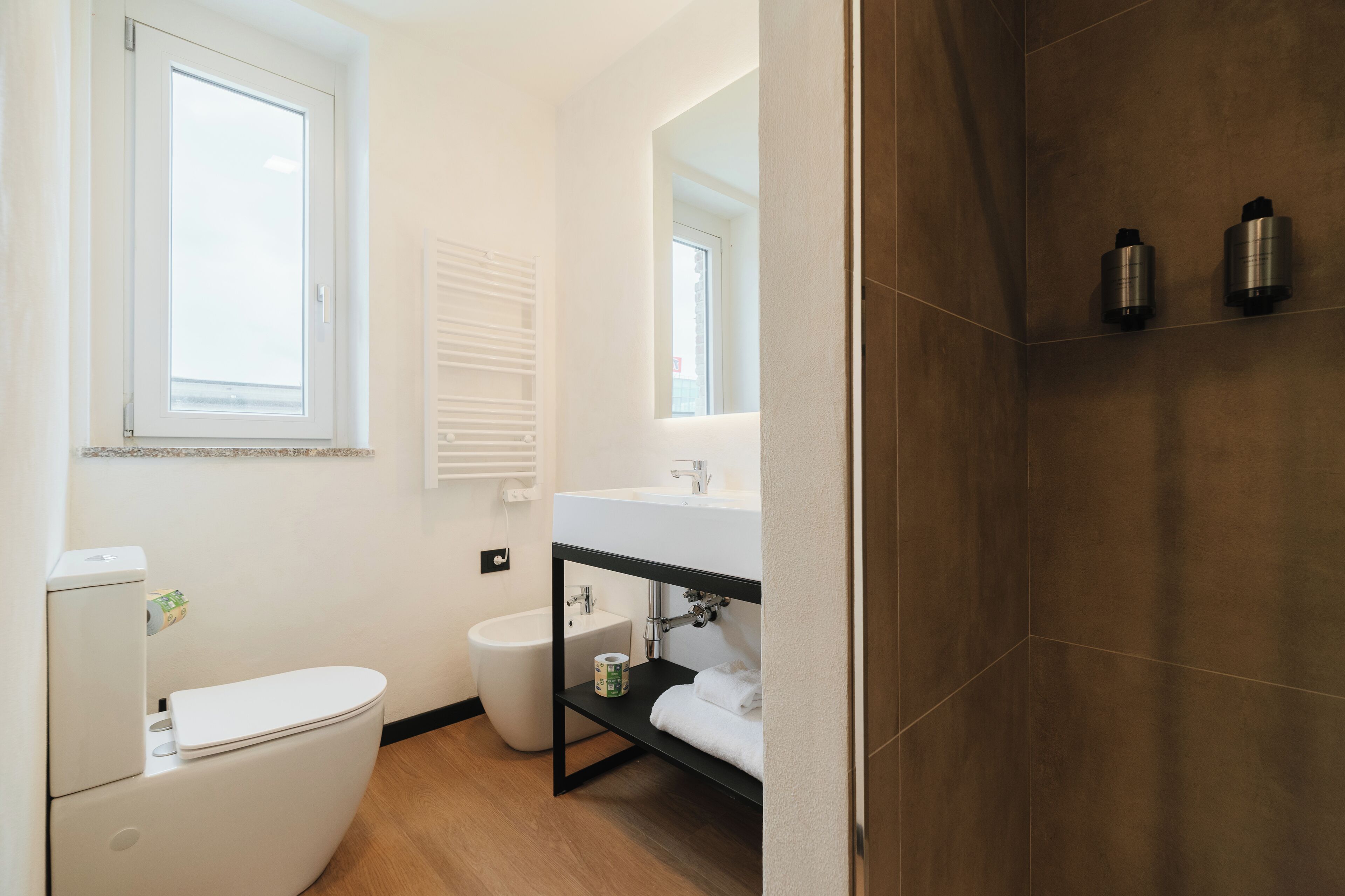 Un baño moderno con inodoro, bidé y lavamanos con espejo superior.