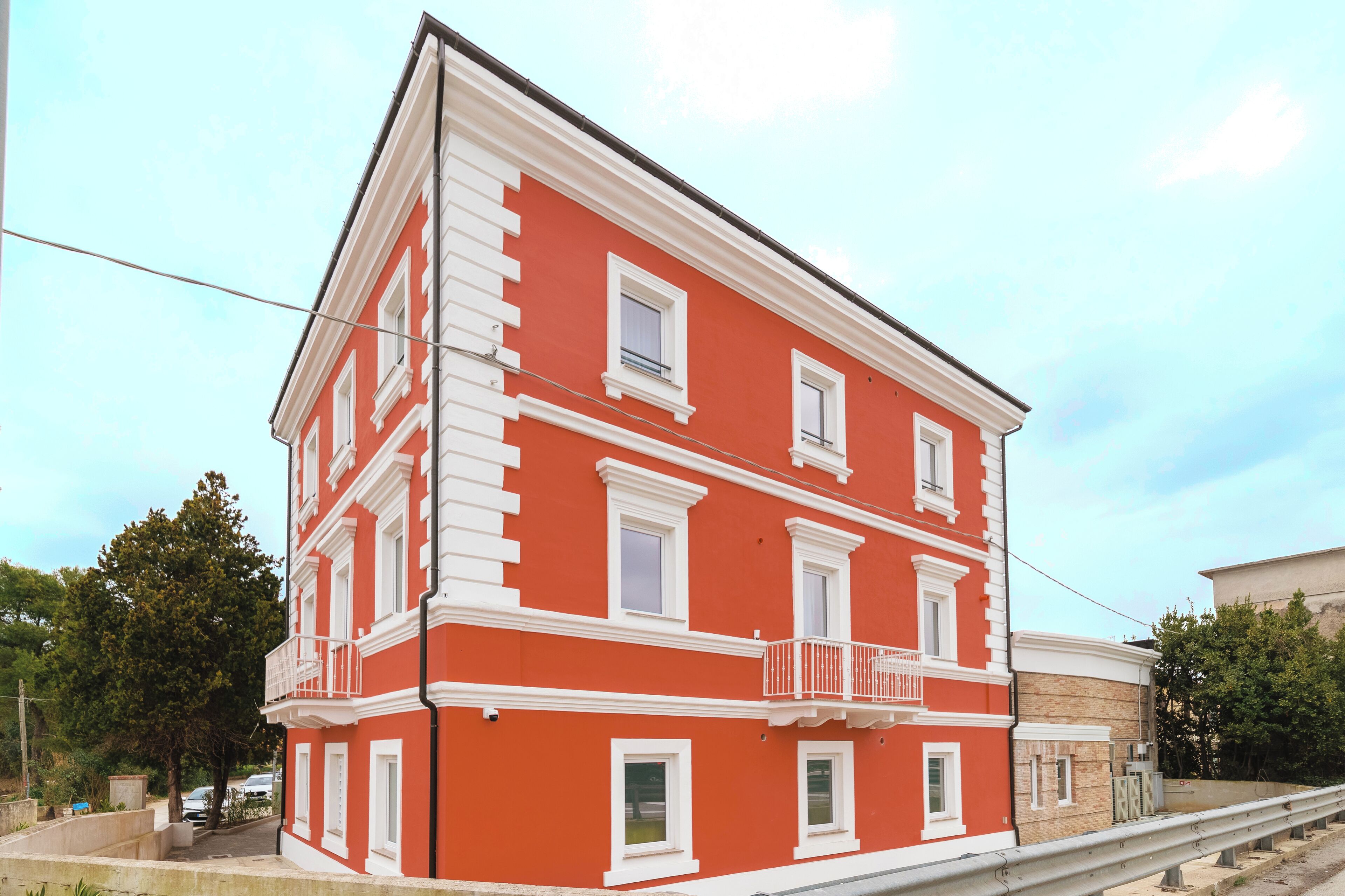 A red and white building with multiple windows and a balcony.