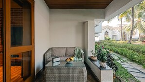 A covered outdoor seating area with a wicker sofa, a glass-top table with a bowl of fruit, and a potted plant. - Charming 1-bedroom apartment in delightful Arpora with WiFi, AC, fitness room (Arpora)