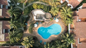 An aerial view of a residential area with a swimming pool surrounded by palm trees and a circular patio area. - Charming 1-bedroom apartment in delightful Arpora with WiFi, AC, fitness room (Arpora)
