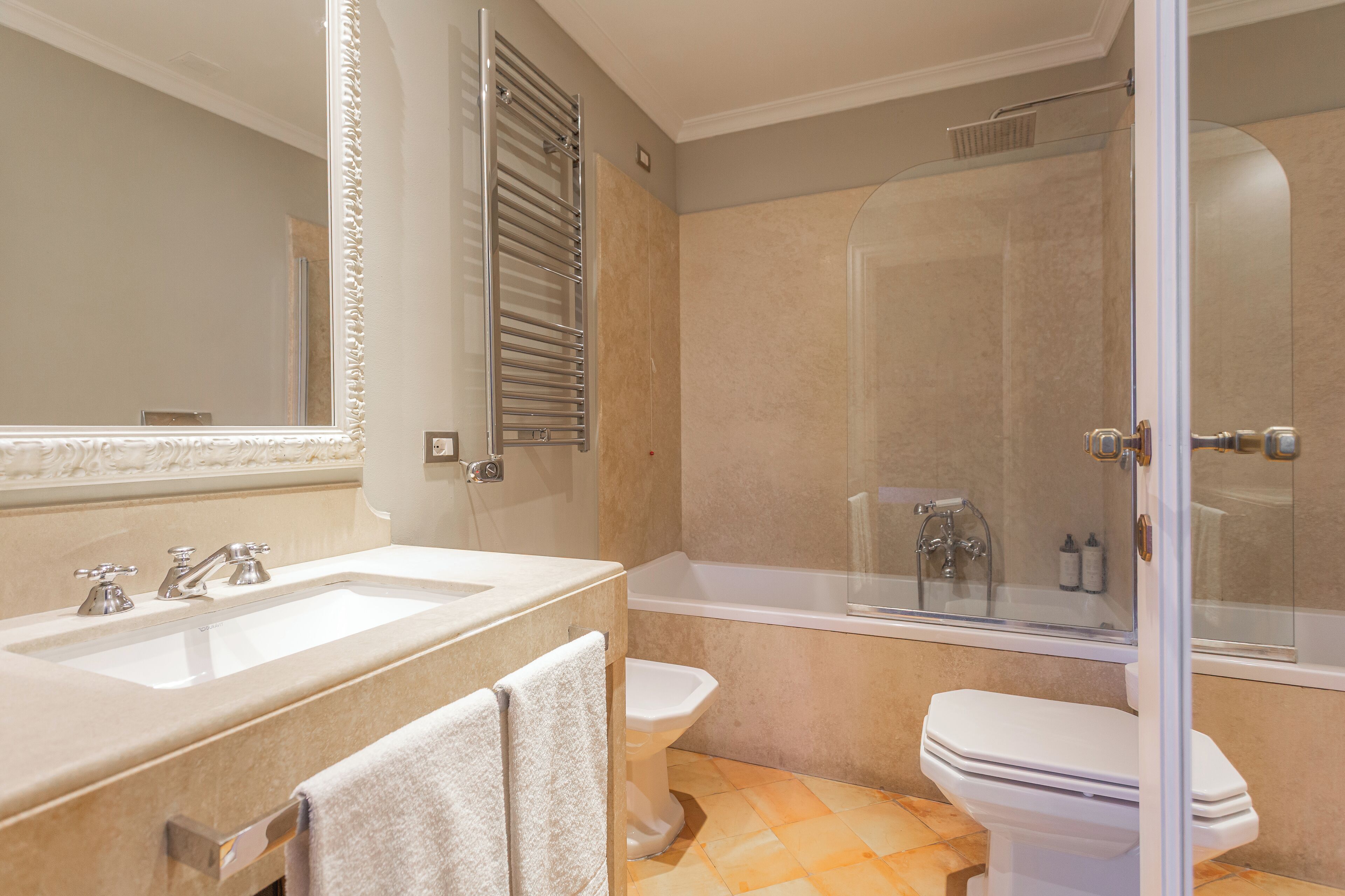Un baño con lavamanos doble, inodoro y ducha con cerramiento de vidrio.