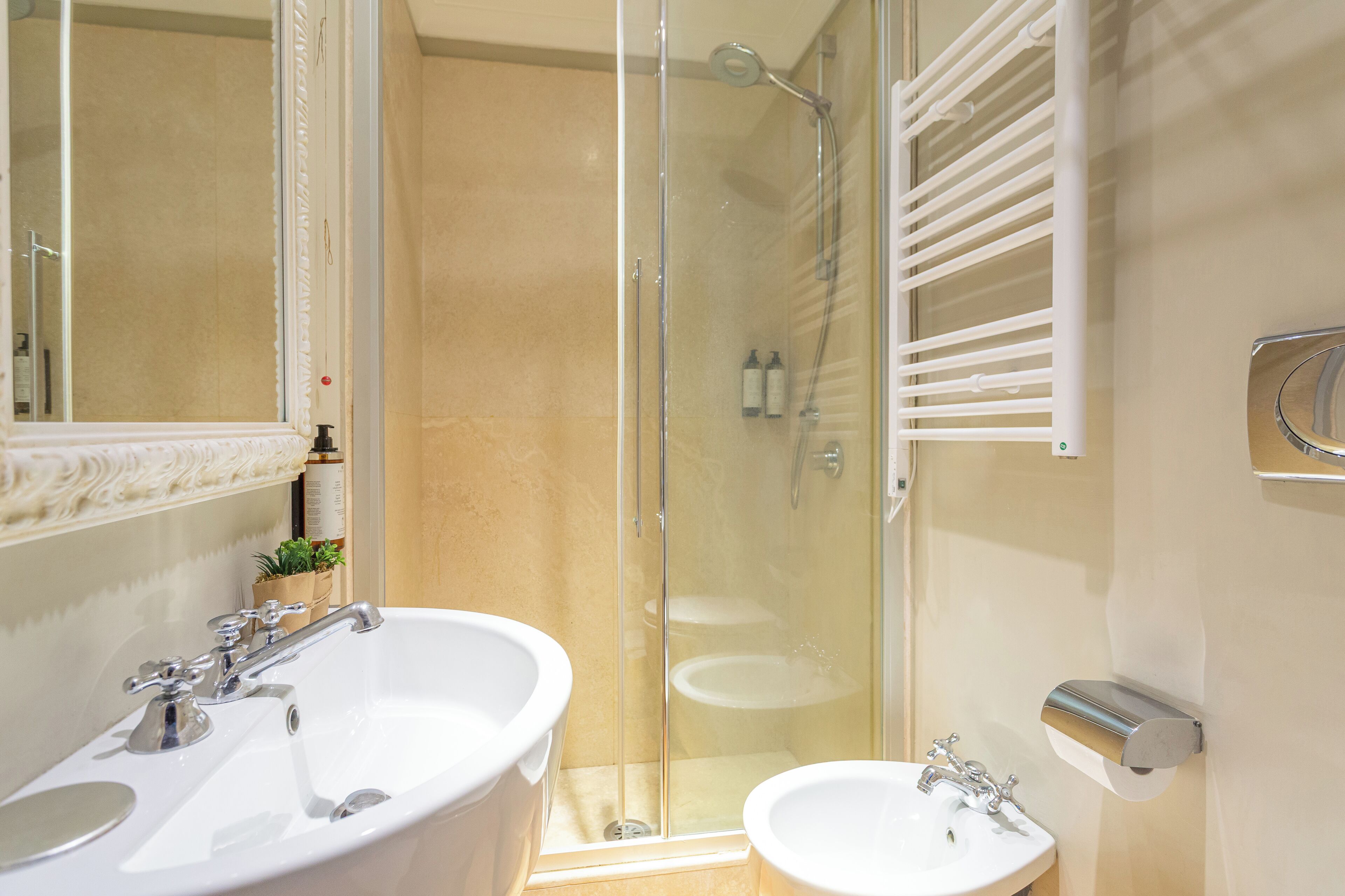 A bathroom with two sinks, a shower, and a glass-enclosed shower area.