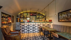A bar area with a checkered floor, leather chairs, and tables. There are shelves with bottles and glasses behind the bar. - Hotel Parrasio (Rome)