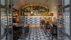 A bar area with a checkered floor, bar stools, and a variety of bottles on shelves. - Hotel Parrasio (Rome)