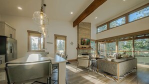 A spacious kitchen with a large island, a dining area with a sofa, and a stone fireplace. - Wilderness Club Cabin Sleeps 7 (Eureka)