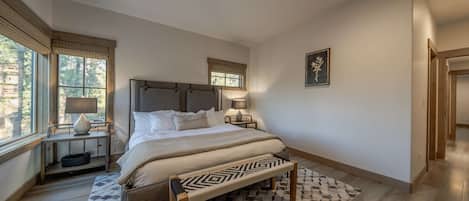 Une chambre à coucher avec un lit, des tables de chevet, un banc et une fenêtre.