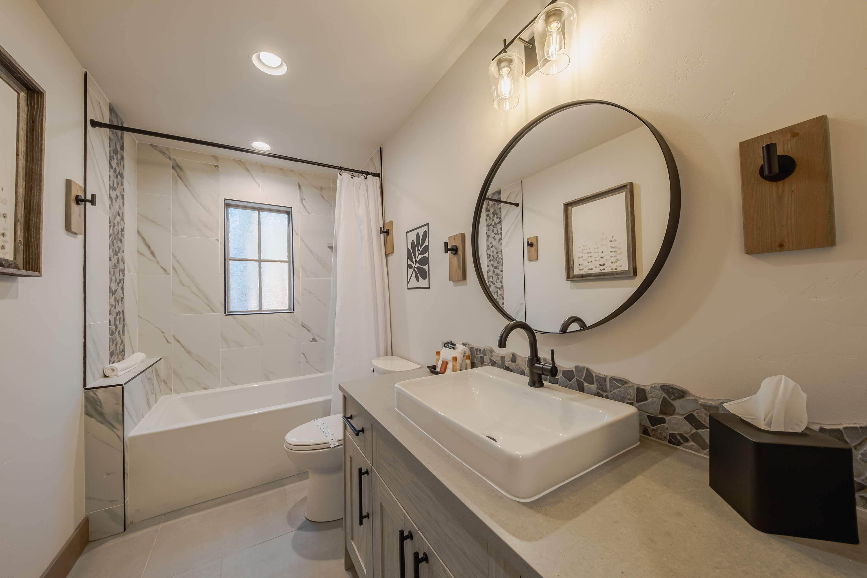 A modern bathroom with a bathtub, toilet, and a large sink.