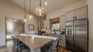 A modern kitchen with a large island, stainless steel appliances, and pendant lighting. - Wilderness Club Cabin Sleeps 7 (Eureka)