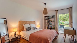 Une chambre à coucher comprenant un lit, des lampes de chevet, une tête de lit en bois, une bibliothèque et un bureau avec une chaise.