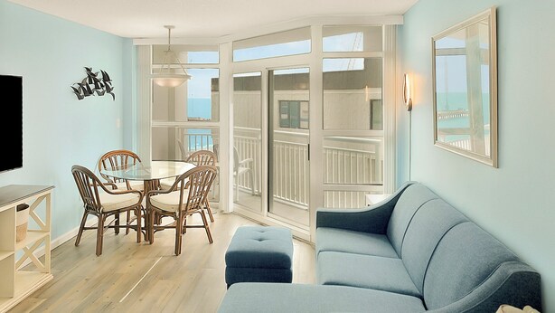 A dining area with a table and chairs, a sofa, and a TV.