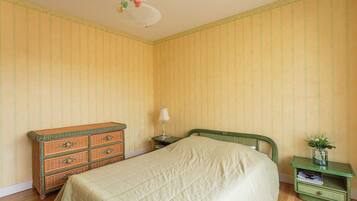 A bedroom with a bed, dresser, nightstand, and a small table with a vase.