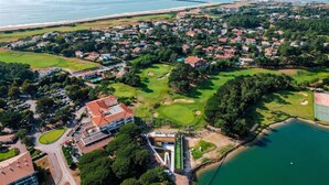 An aerial view of a coastal town with a golf course, residential areas, and a large body of water.