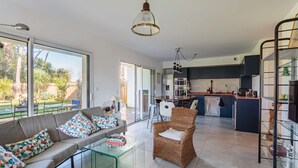 A spacious living area with a sofa, a wicker chair, and a glass coffee table.