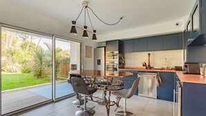 A modern kitchen with a large island, stainless steel appliances, and a sliding glass door to a backyard.
