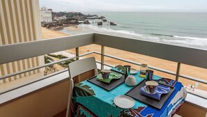 A balcony with a table set for two, overlooking a beach and ocean. - - (BIARRITZ)