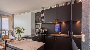 A modern kitchen with black cabinets, a marble countertop, and a built-in oven. - - (BIARRITZ)