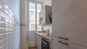 Une cuisine moderne avec un dosseret de carrelage blanc, un plancher en bois et des appareils électroménagers intégrés.