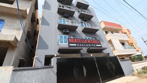 Ein mehrstöckiges Gebäude mit Balkonen und einem Schild mit der Aufschrift 'NEATFLIX & CHILD EXCLUSIVE'.